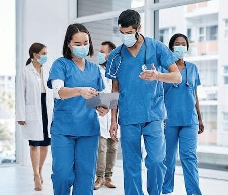 Eles se comunicam com frequencia e compartilham recursos quando necessario Foto de dois medicos fazendo anotacoes enquanto caminham em um hospital movimentado   Foto Premium e1745329648369